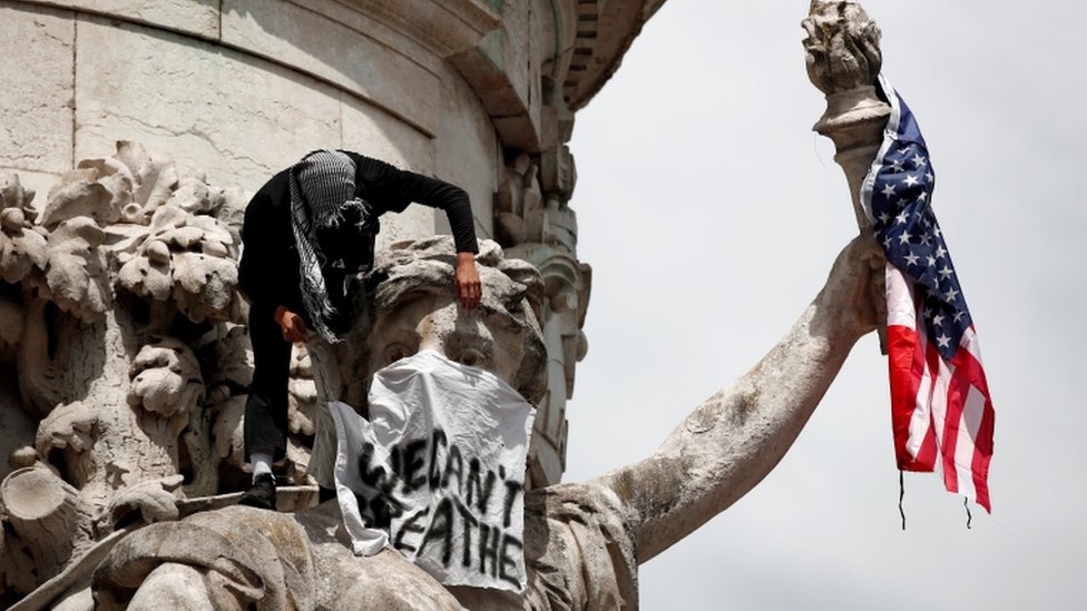 Protesti u Evropi: U Londonu više od 100 uhapšenih, većinom desničara, u Parizu policija protiv antirasističkih demonstranata 5 A banner and a US flag are placed on the Monument a la Republique during a protest against police brutality and the death in Minneapolis police custody of George Floyd