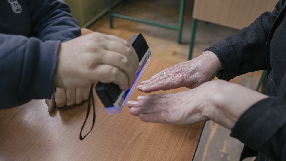 U fotografijama: Izbori u Srbiji 2 Članovi biračog odbora UV lampom proveravaju da li je neko već glasao