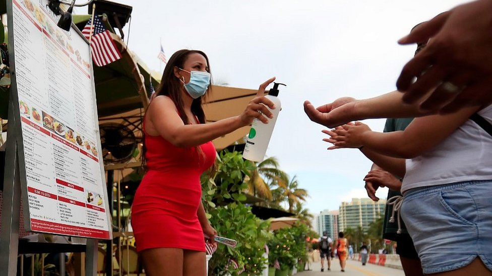 Hostess provides hand sanitiser at restaurant in Miami, 3 Jul 20