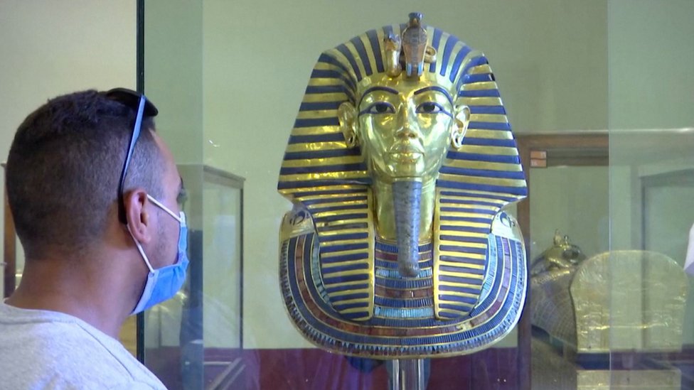 muškarac s maskom pred statuom kralja tutankamona u kairu