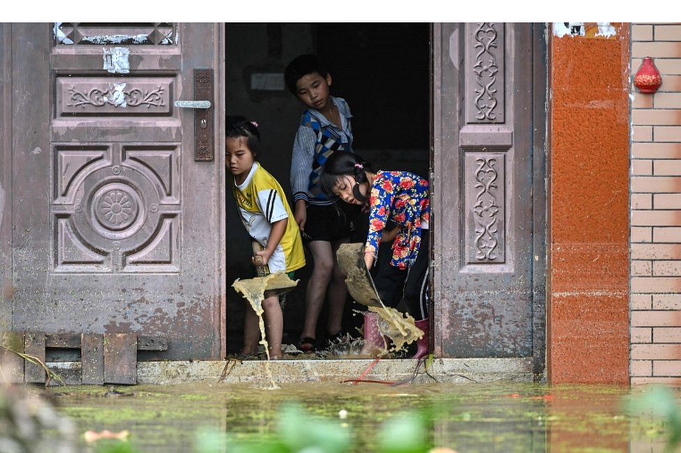 Deca izbacuju vodu iz porodične kuće u selu Longkou, koje je poplavljeno zbog velikih kiša, 16. jul 2020.