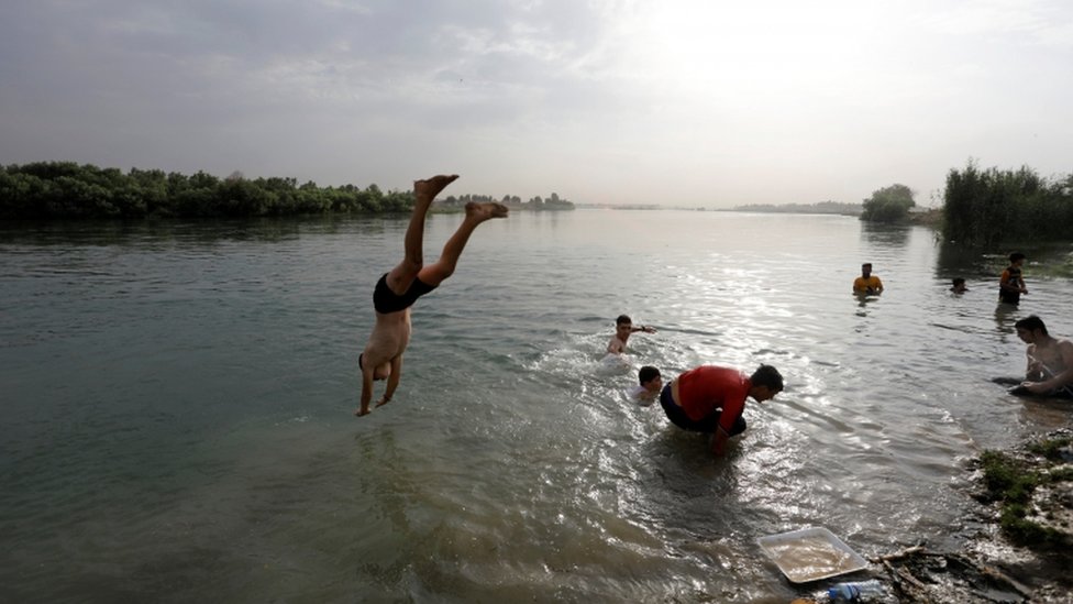 An Iraqi boy dives into the Tigris river in Mosul