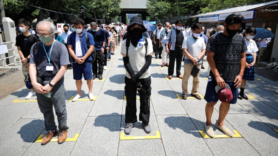 People practice social distancing while paying a silent tribute during their visit to Yasukuni Shrine