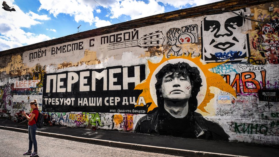 Tourists take photos in front of a Tsoi Wall, a memorial to Viktor Tsoi, in downtown Moscow
