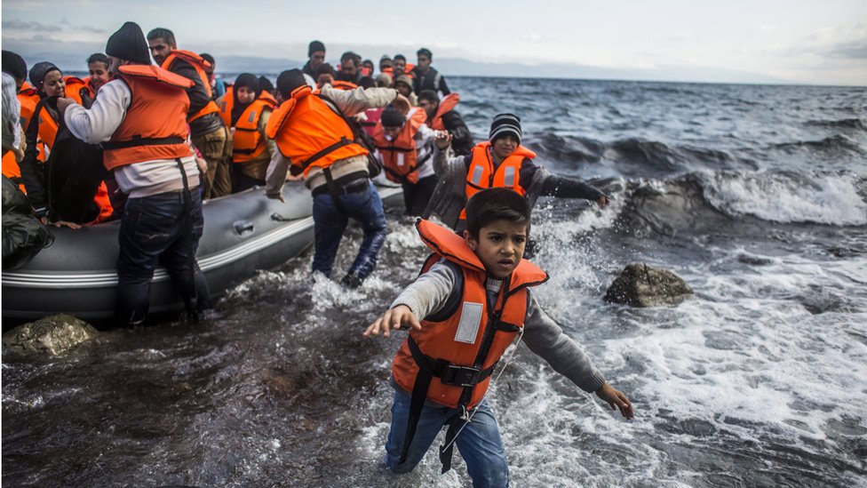 Image shows refugees arriving on the shores of the Greek island of Lesbos in October 2015