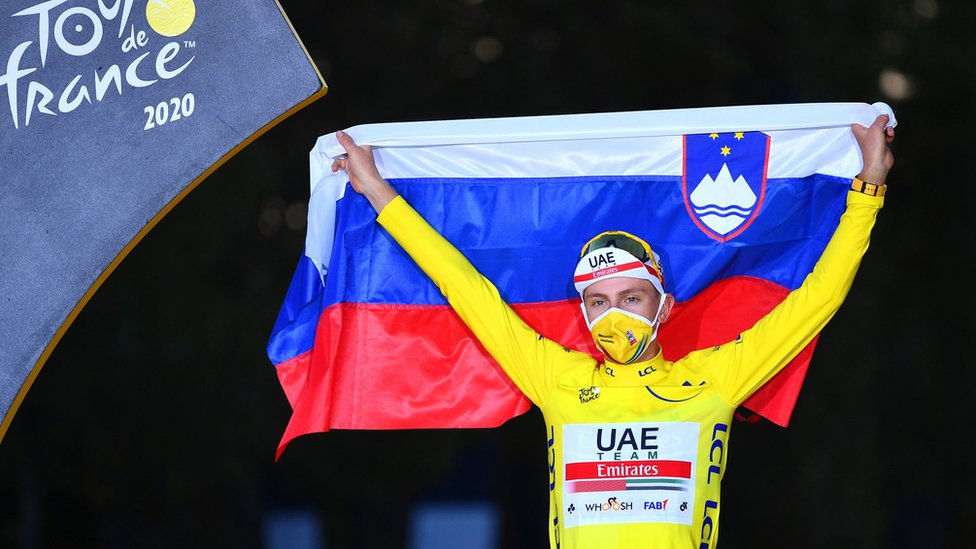 Tadej Pogacar holds up the Slovenian flag in celebration after winning the 2020 Tour de France