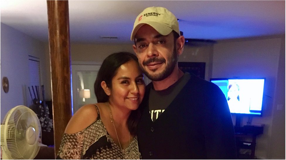 Yazmin stands with her partner at their home