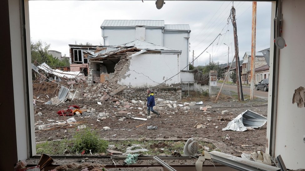Man walks past house damaged by shelling in the regional capital Stepanakert