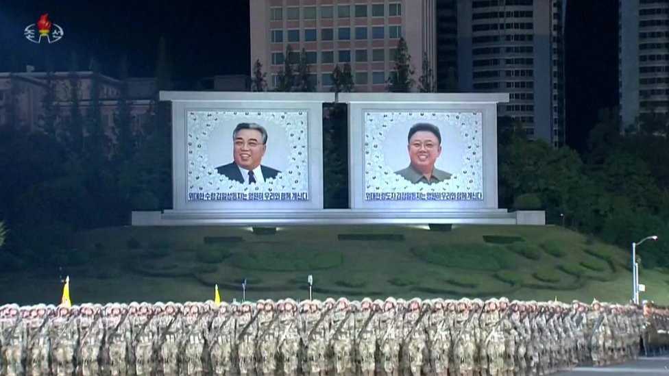 Soldiers stand in front of images of Kim Il-Sung and Kim Jong-il