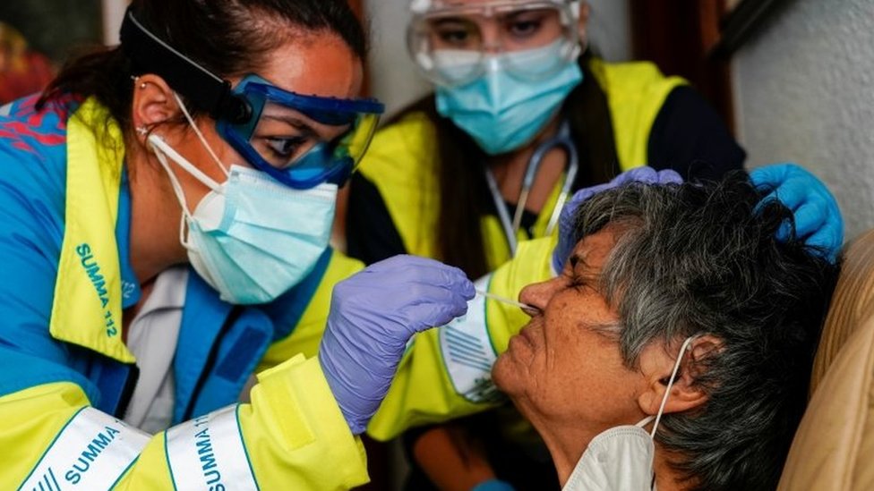 A medic tests an elderly woman for Covid-19 in Madrid