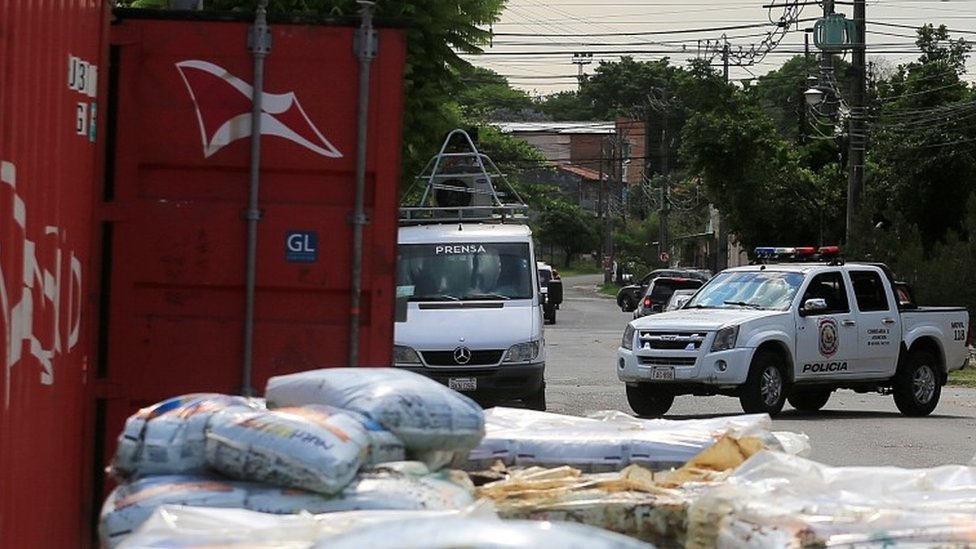 A police vehicle is seen near a container where the authorities found decomposed bodies inside a fertiliser shipment