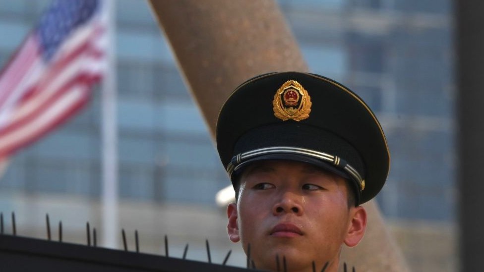 A paramilitary policeman looks on past the US flag on the embassy compounds in Beijing