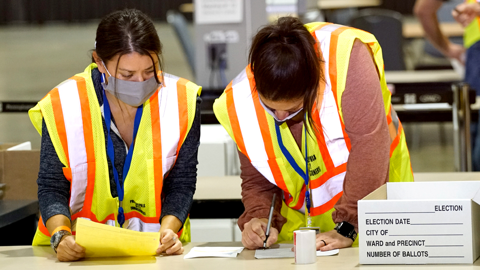 Two electoral workers count ballots on a table