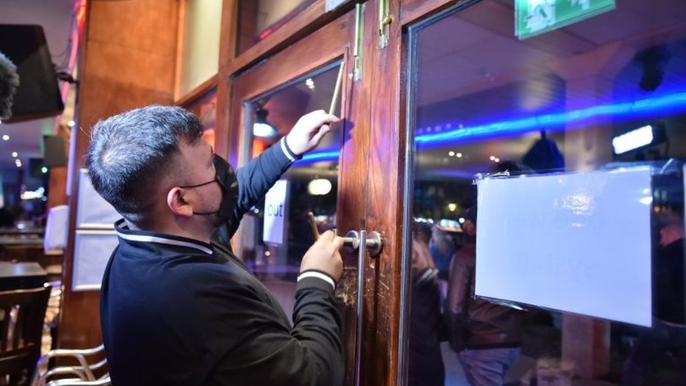 Korona virus: U Srbiji sve manje mesta u bolnicama, karantin u Engleskoj, u SAD dnevni rekord zaraženih 1 A worker shuts the doors in a bar in Bristol city centre, ahead of a national lockdown for England from Thursday