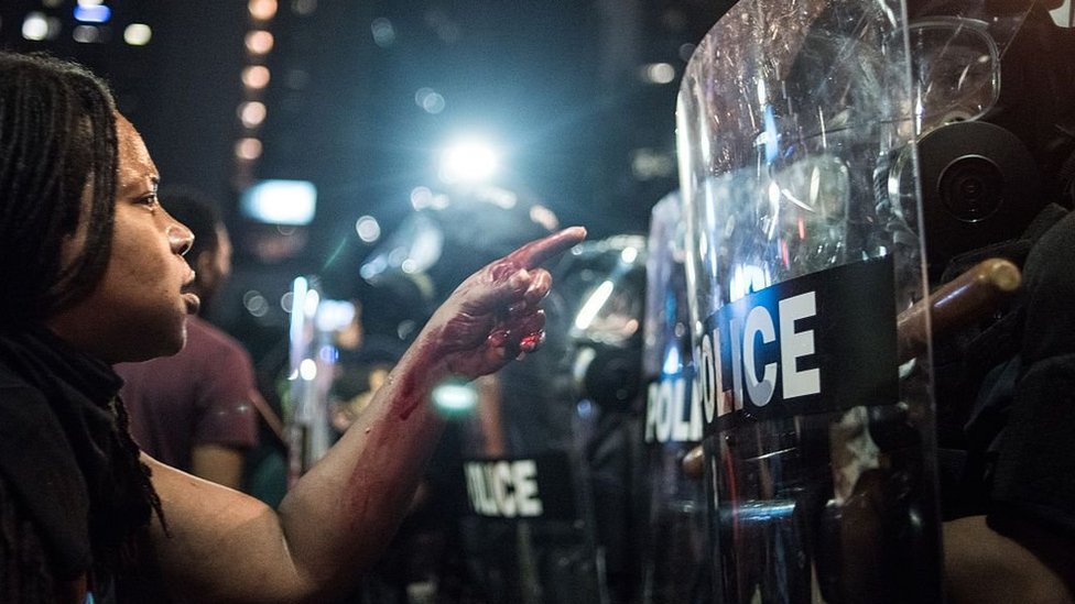 A Black Lives Matter protester faces a line of riot police