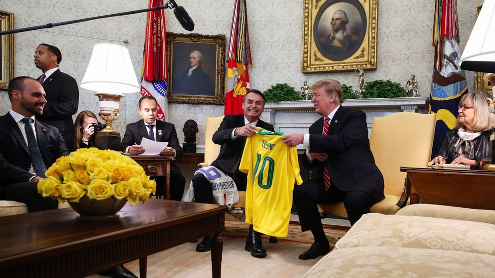 Američki izbori 2020: Šta Trampov poraz znači za „čvrste momke“ sa desnice 2 The Brazilian president, Jair Bolsonaro, gifts Trump a Brazil football jersey with his name on it during a meeting at the White House Oval Office on 19/03/2019