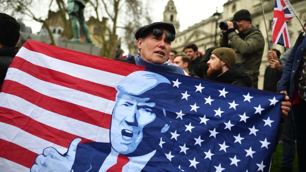 A Brexit supporter holds up a flag, inspired in the American flag, with Trump's face on it, as the UK counted down to exit the EU on 31 January 2020 in London