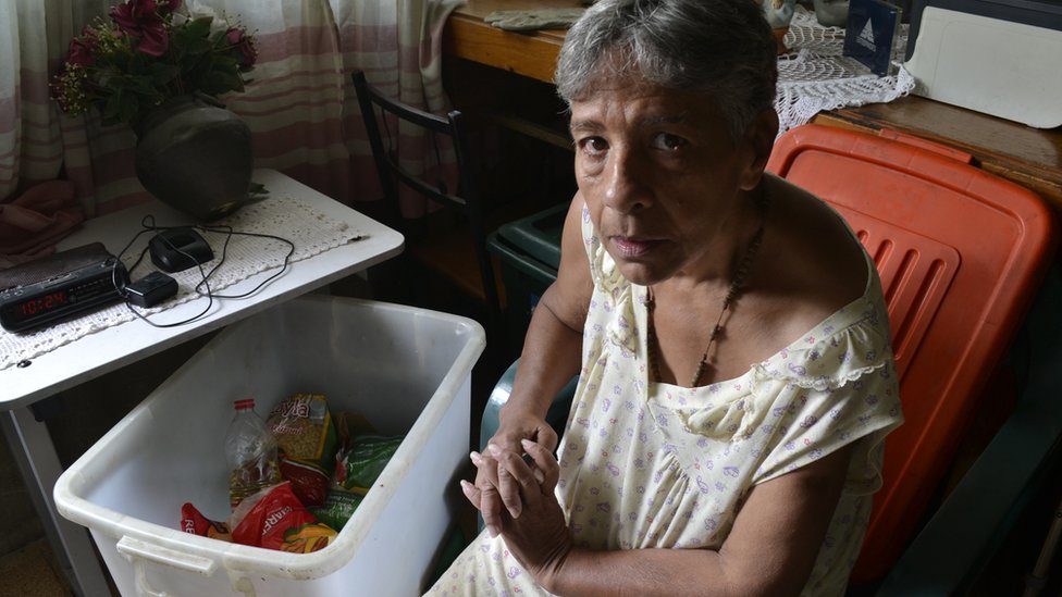 Norma Mújica next to a government food box