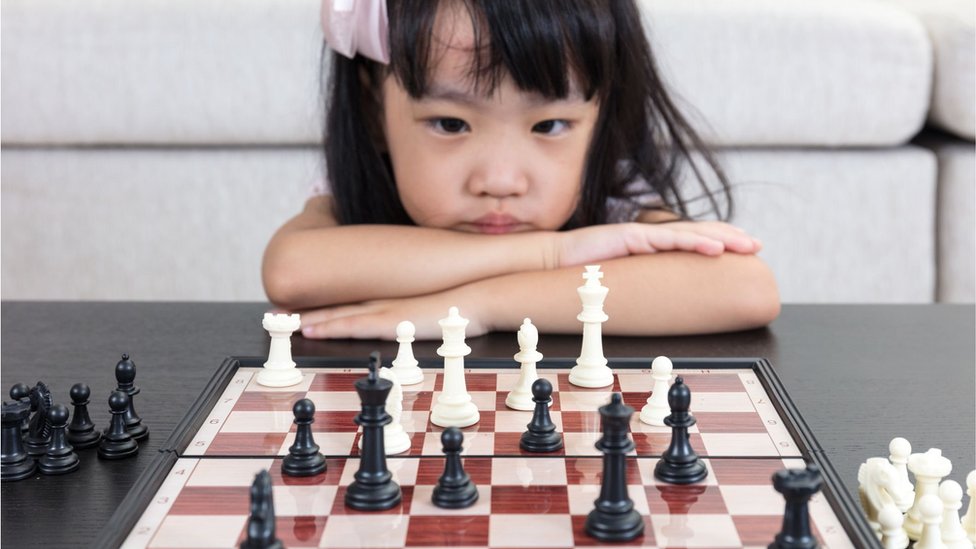 A girl looking serious while staring at a chess board
