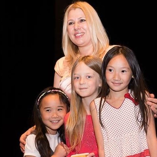 Susan Polgar poses for a picture hugging young girl chess players