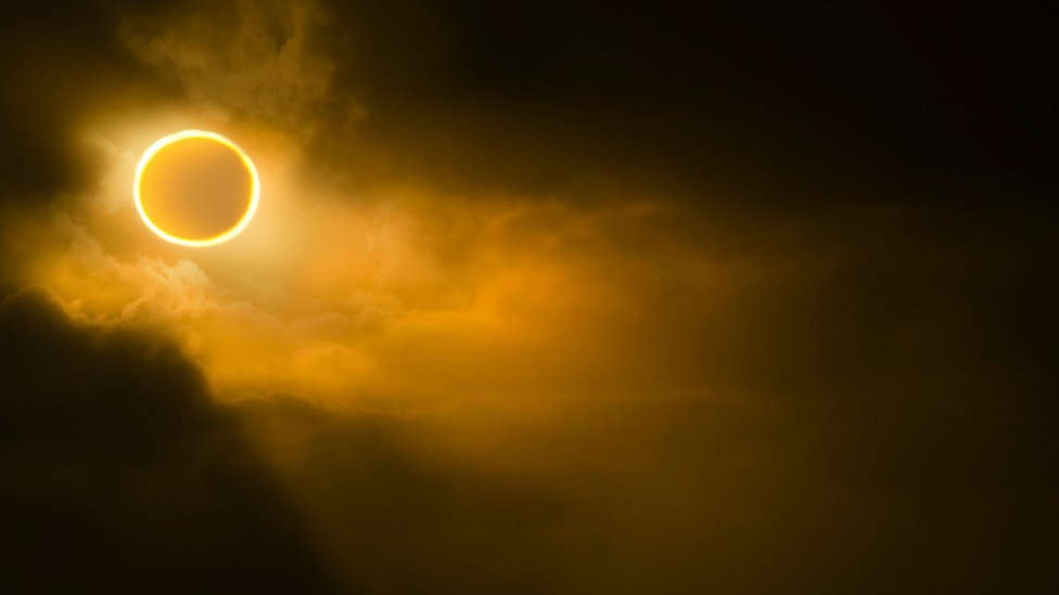 Low angle view of solar eclipse in sky during foggy weather.