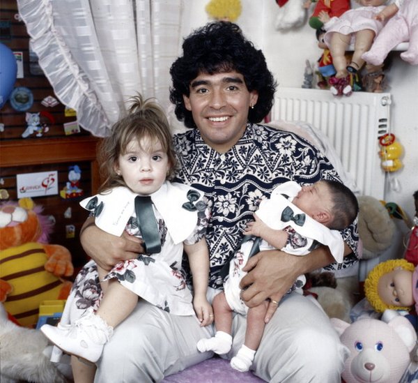 Maradona sitting in a small bedroom with his daughters Dalma e Giannina in his arms