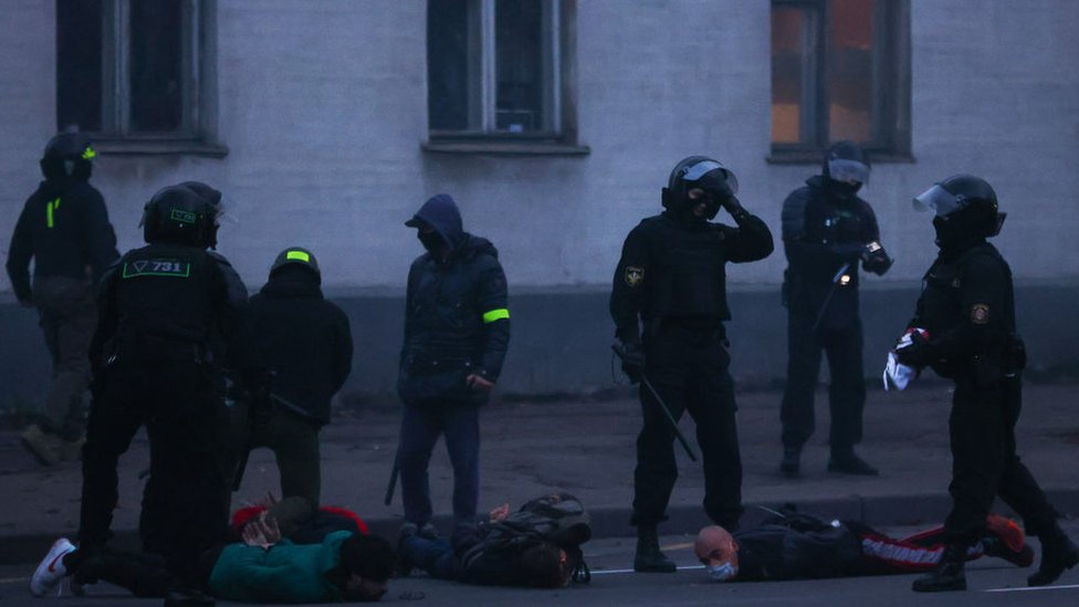 Police hold demonstrators face-down on the floor on 25 October