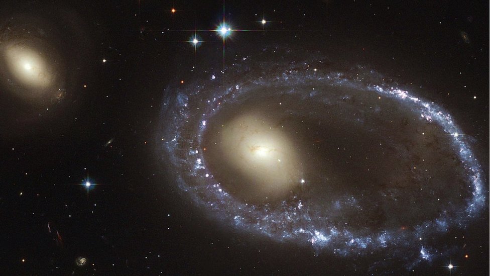 Hubble Space Telescope (HST) image from 2017 - colour image of a faraway galaxy resembling a diamond-encrusted bracelet, a ring of brilliant blue star clusters wraps around the yellowish nucleus of what was once a normal spiral galaxy.