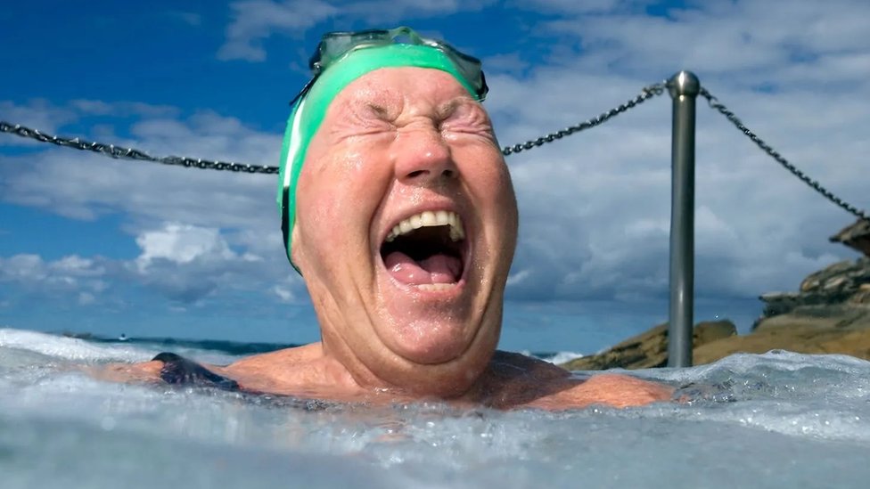 An elderly woman laughs in a hot tub