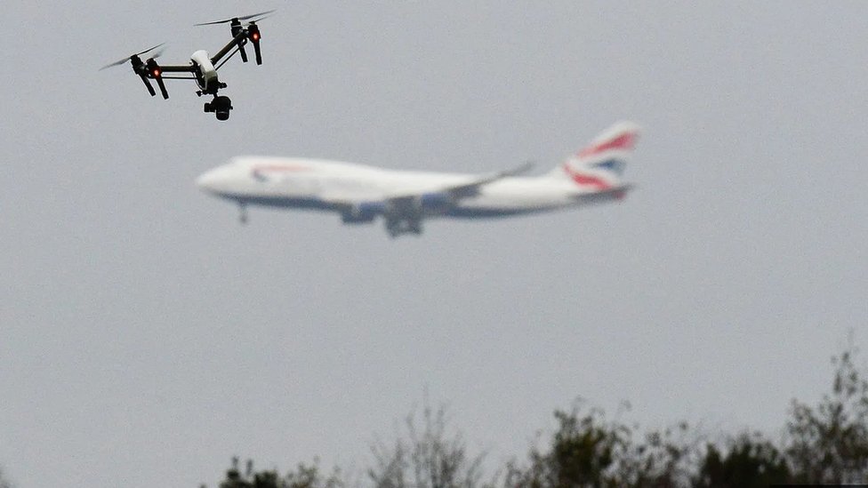 Drone flying in a West London park with a passenger plane in the background