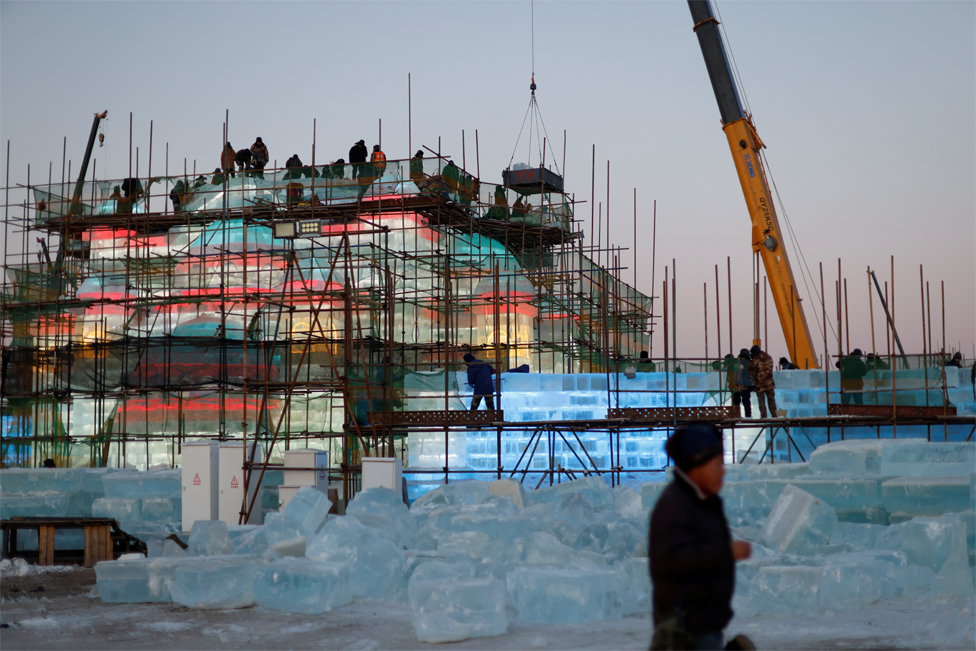 Workers on scaffolding build an ice structure at the site of the Harbin International Ice and Snow Festival