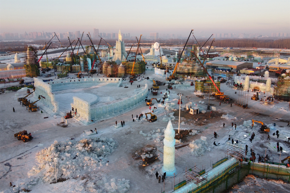 Workers build ice structures at the site of the Harbin International Ice and Snow Festival