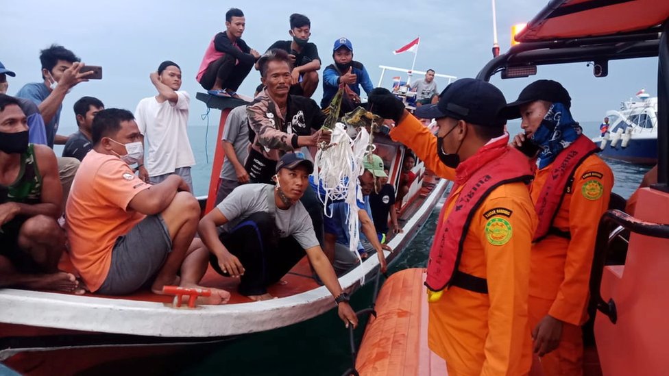 Local fishermen and rescuers hold suspected remains of the Sriwijaya Air plane flight SJ182, which crashed into the sea near Jakarta