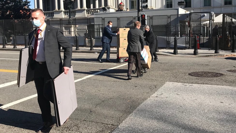 Staff carry pictures and pictures out of the White House
