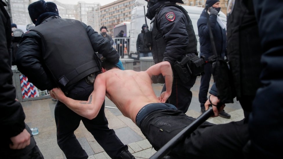 Law enforcement officers detain and drag topless man during a rally in Moscow