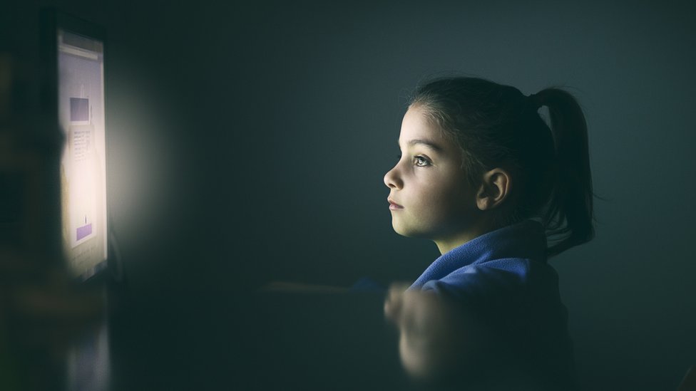 Girl illuminated by the glow of a screen