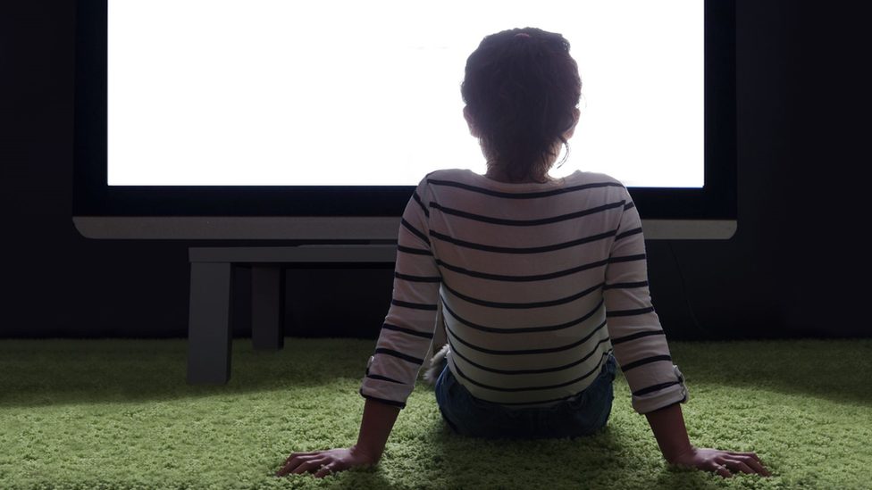 Child staring at a huge screen