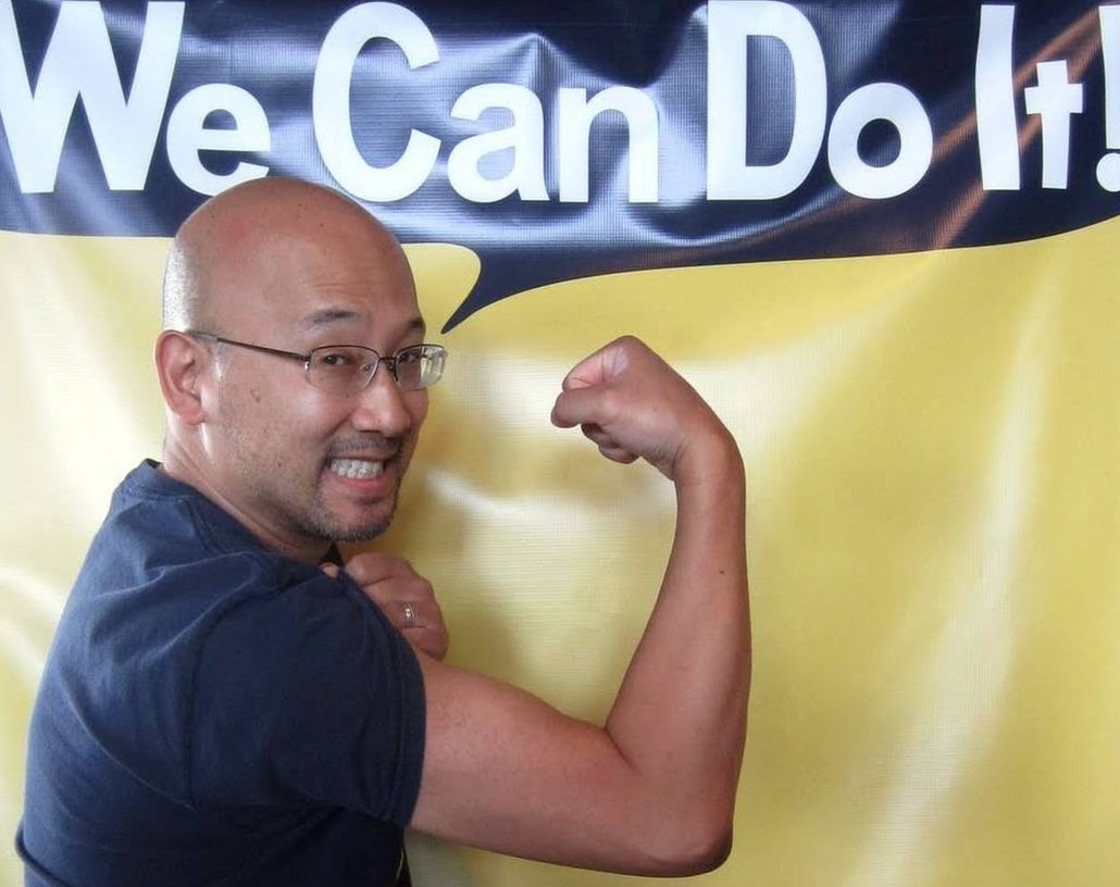 Eugene Hung fléchissant ses muscles sous une bannière disant : "Nous pouvons le faire !"