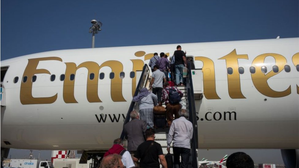 Korona virus, lažni testovi i Avganistan: Na šta su sve ljudi spremni samo da putuju 2 Air passengers climb stairs to an Emirates Airlines Boeing 777 passenger jet departing to Kabul from Dubai