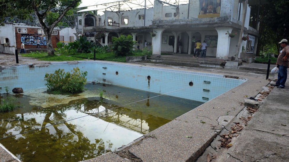 Visitors look at the swimming pool and destroyed mansion of drug trafficker Pablo Escobar, inside the Hacineda Napoles theme park