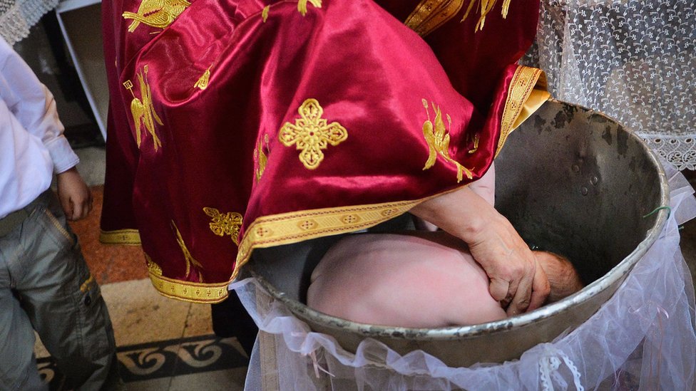 Rumunija i pravoslavna crkva: Zbog slučaja bebe koja je preminula na krštenju pokrenuta inicijativa da se obred izmeni 1 A Romanian Orthodox priest immerses a baby's head during a baptism (file pic)