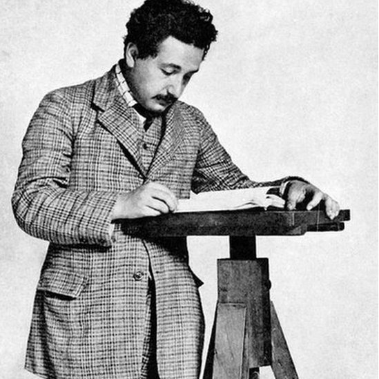 Black and white photo of Albert Einstein reading a book. He is believed to be 26 years old in this picture.
