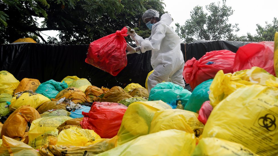 A person walking amid bags of medical waste