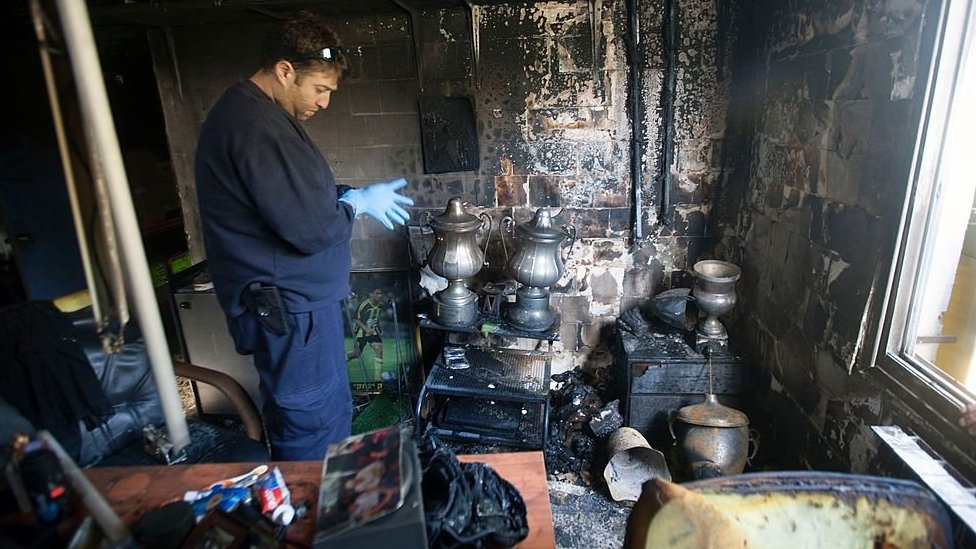 A policeman examines the torched offices of Beitar Jerusalem in 2013
