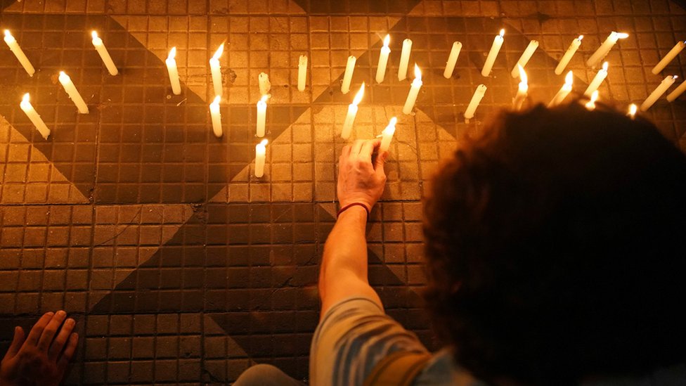 Demonstrators light candles and place them on the floor