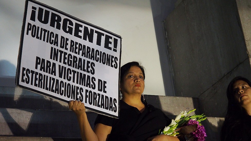 A women holds a sign during a protest demanding compensation in 2017
