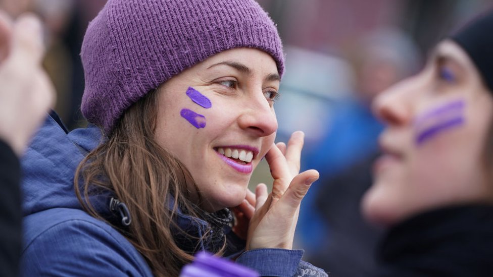 A woman paints purple stripes on her face during a feminist women's bicycle protest on International Women's Day on March 08, 2020 in Berlin, Germany