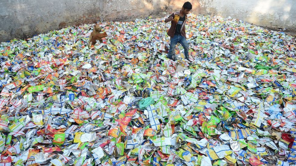 A boy searches for food in polythene packets at a roadside in India