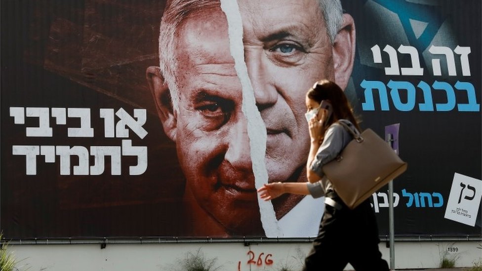 Woman walks past Israel election campaign poster in Tel Aviv (14/03/21)