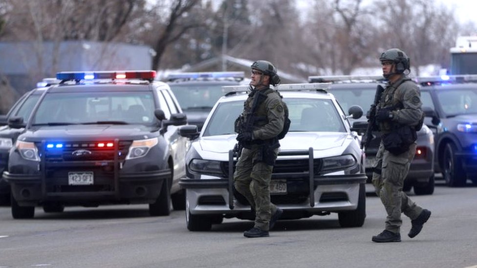 Law enforcement officers stand at the perimeter of a shooting site at King Soopers grocery store in Boulder, Colorado